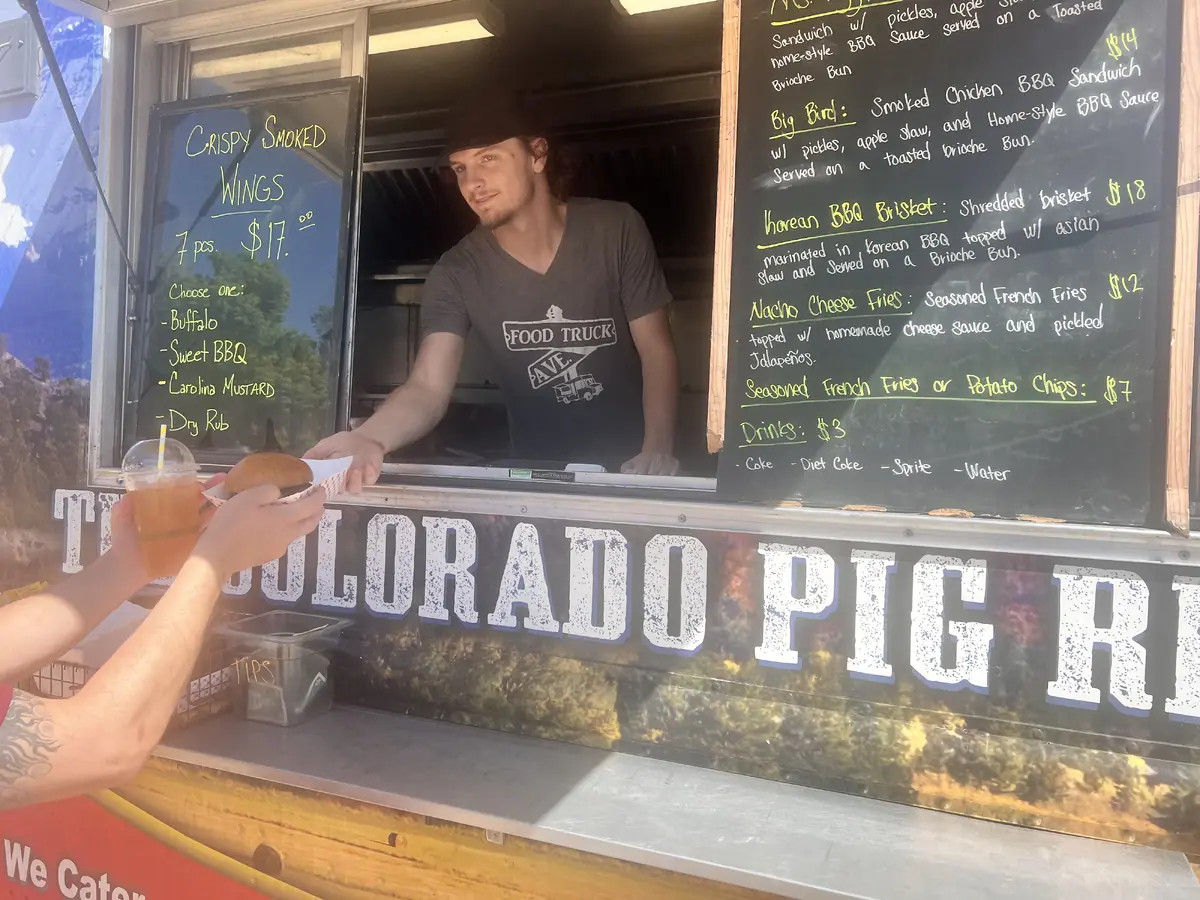 Colorado Pig Rig food truck serving window with BBQ sandwiches being prepared for an event